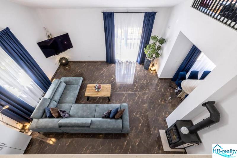 Villa kilátással a nappalira, kék kanapéval és márványpadlóval.