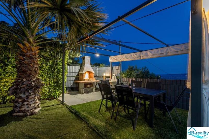 A Kaštela-i villa pálmakertje pergolával, kandallóval és asztallal.