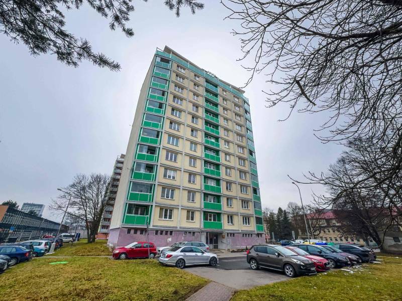 Magas lakóépület a Banská Bystrica SNP sugárútján parkolóval az előtérben.