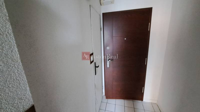 Az egyszobás lakás bejárati ajtaja csempével és fehér falakkal.