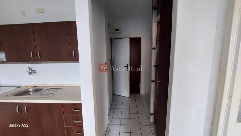 Konyha sötét szekrényekkel és fehér csempékkel egy egyszobás lakásban.