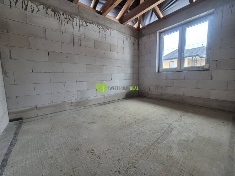 Betonpadló, festetlen téglák és fa gerendák a családi ház belsejében.