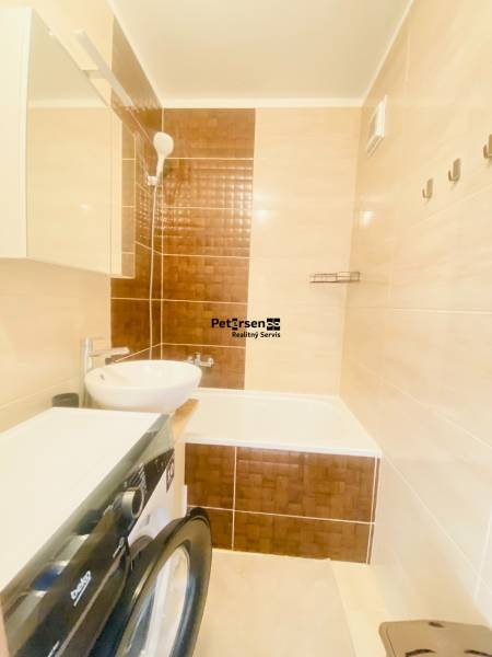 Fürdőszoba egy kétszobás lakásban mosdóval, káddal és mosógéppel.