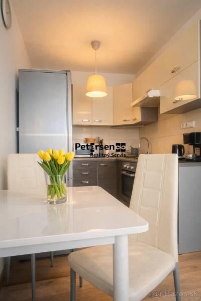 Konyha egy kétszobás lakásban fehér étkezőasztallal és sárga tulipánokkal.