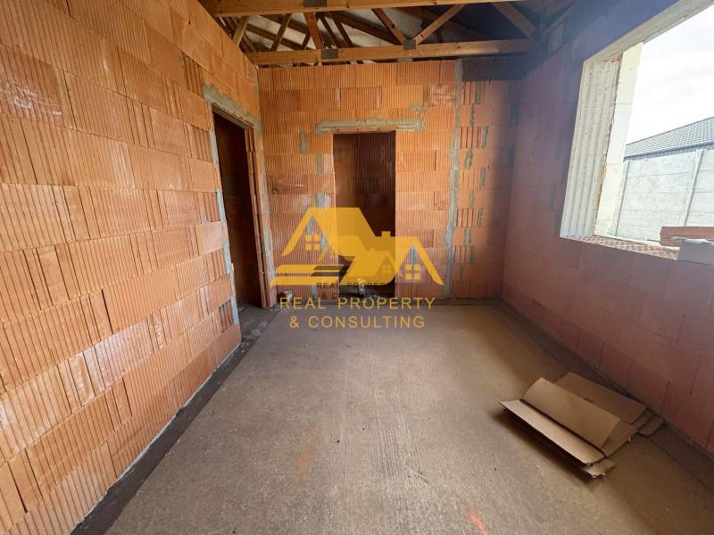 Egy építés alatt álló családi ház belső tere, látható téglákkal és építőanyagokkal.