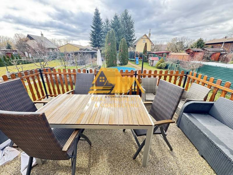 Az újvári ház teraszán van egy asztal székekkel és kanapéval.