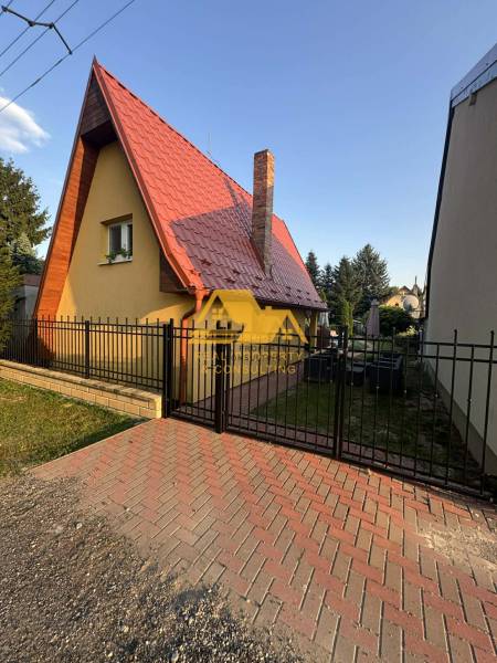 Ház az utcán Érsekújváron, hegyes tetővel és téglakéménnyel.