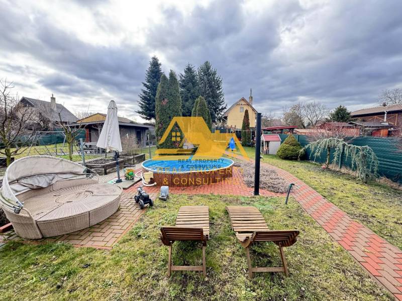 Kert a ház mellett medencével az utcán Érsekújváron, gondozott zölddel körülvéve.