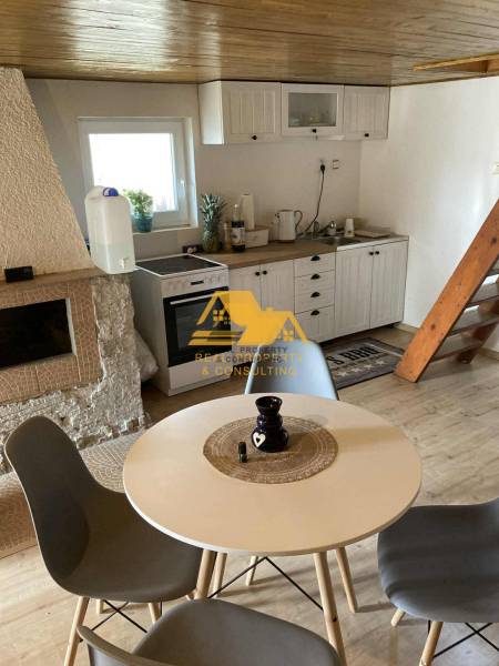 Egy faház belseje asztallal, négy székkel és konyhasarokkal, fa dekorációjú padlóval.