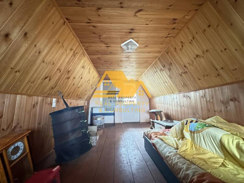 Faház tetőtér fa dekorációval és egyszerű berendezéssel, kellemes pihenőhely.