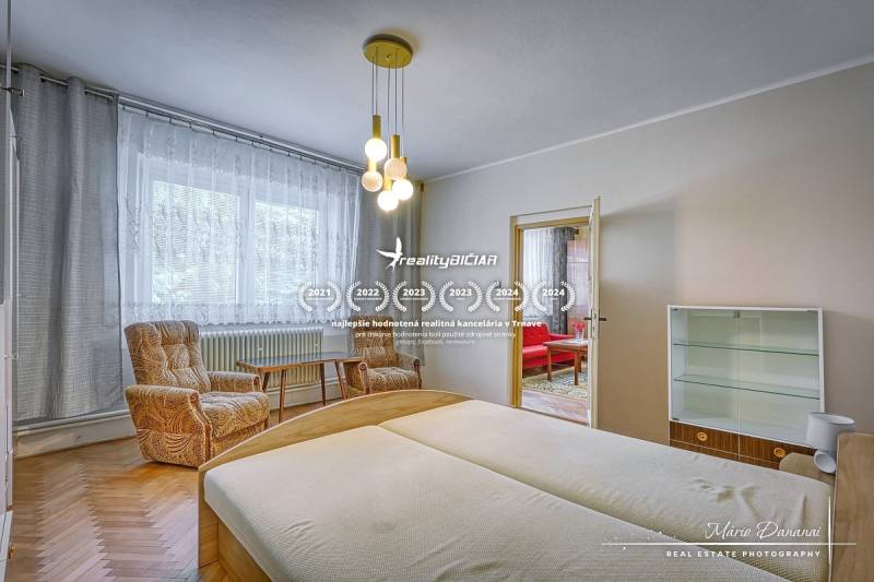 Családi ház hálószobája világos fa bútorokkal és kényelmes fotelekkel.