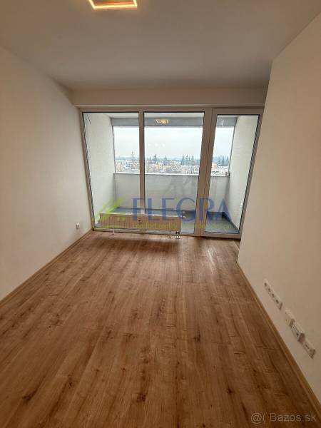 Nappali egy egyszobás lakásban, fa dekorációjú padlóval és nagy ablakokkal.