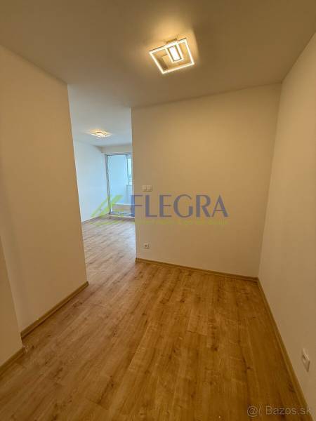 Egy szobás lakás folyosója fa mintázatú padlóval és modern világítással.