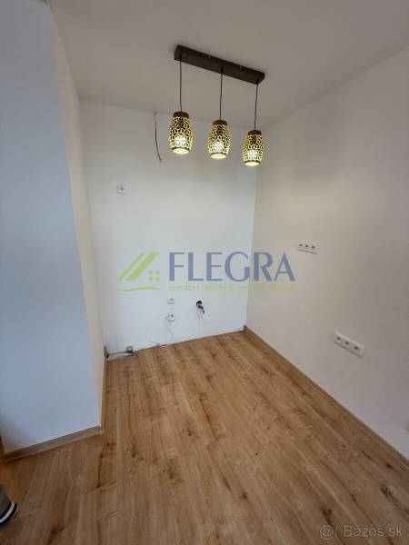 1 szobás lakás belső tere fa mintázatú padlóval és függő világítótestekkel.