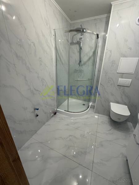 Fürdőszoba márvány burkolattal és zuhanyzóval egy egyszobás lakásban.