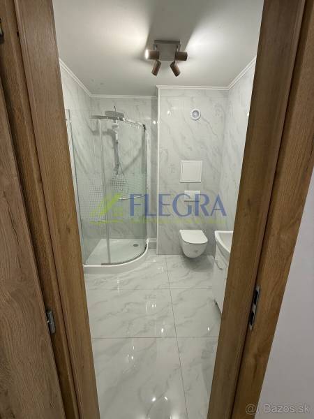 Fürdőszoba egy egyszobás lakásban zuhanyzóval és kerámia burkolattal.