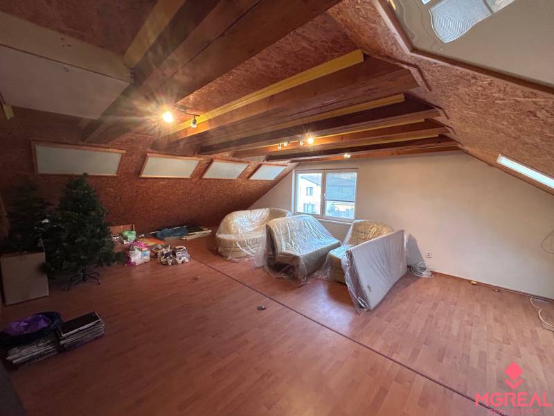 Tetőtéri szoba egy családi házban, fa dekorációjú padlóval és tetőablakokkal.