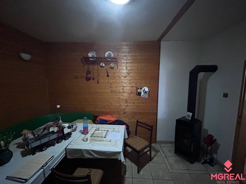 Családi ház fa burkolattal, cserépkályhával és étkezőasztallal.