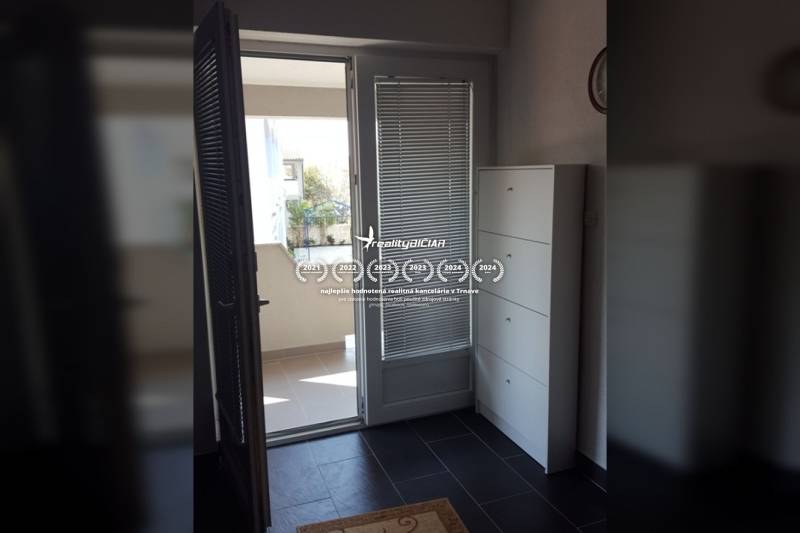 Erkély bejárata családi házban csempézett padlóval és fehér bútorokkal.