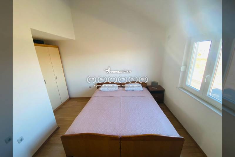 Hálószoba családi házban ággyal, éjjeliszekrénnyel és fa dekorációjú padlóval.