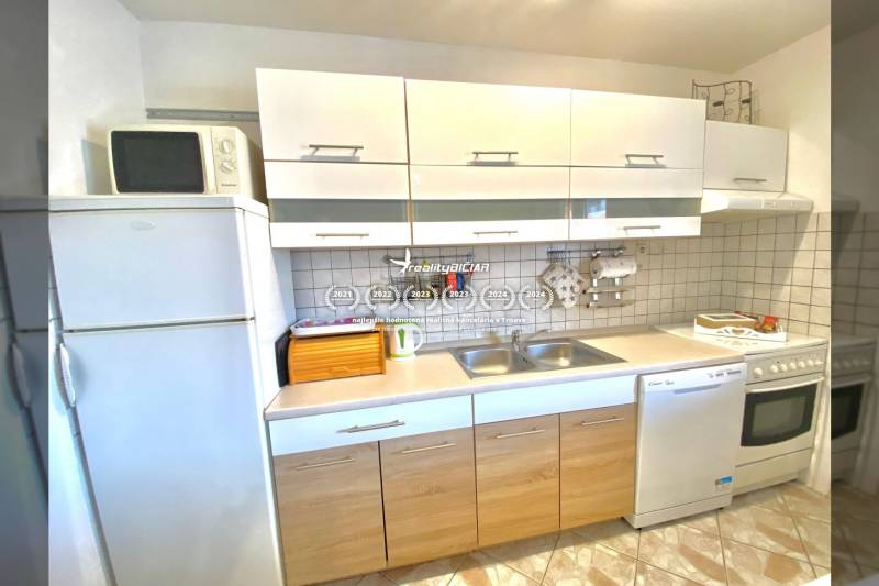 Családi ház konyhája fehér szekrényekkel, tűzhellyel és mikrohullámú sütővel.