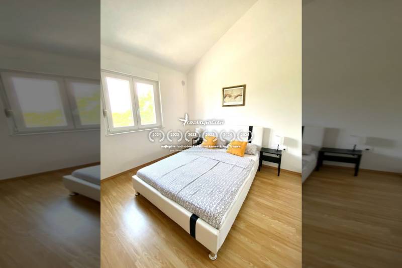 Hálószoba családi házban, fa dekor padlóval, ággyal és ablakkal.