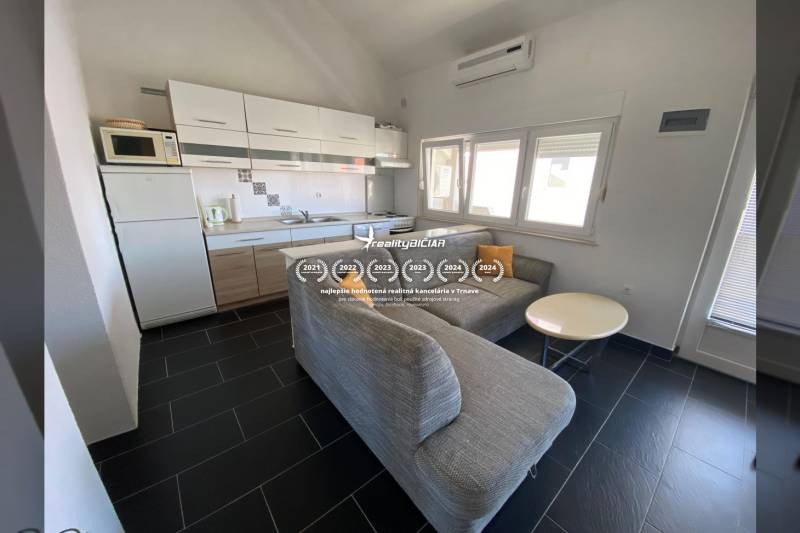 Konyha sarokkanapéval és étkezőasztallal, családi ház, sötét burkolatú padló.