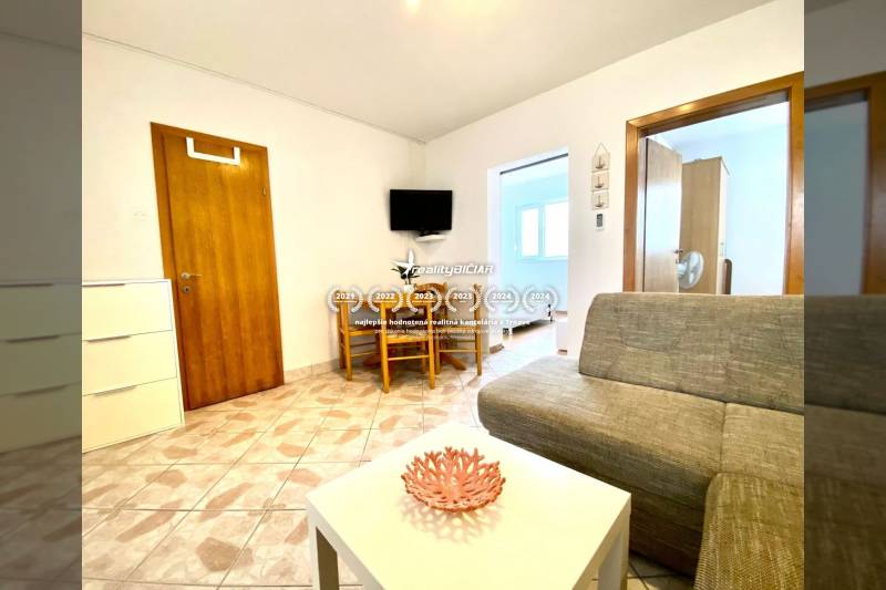 Nappali egy családi házban kanapéval, asztallal és falra szerelt televízióval.