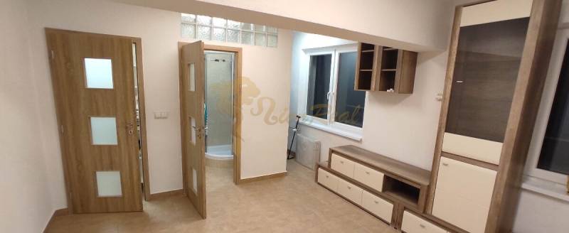 Egyszobás lakás nappalija fa mintázatú padlóval és semleges tónusú bútorokkal.