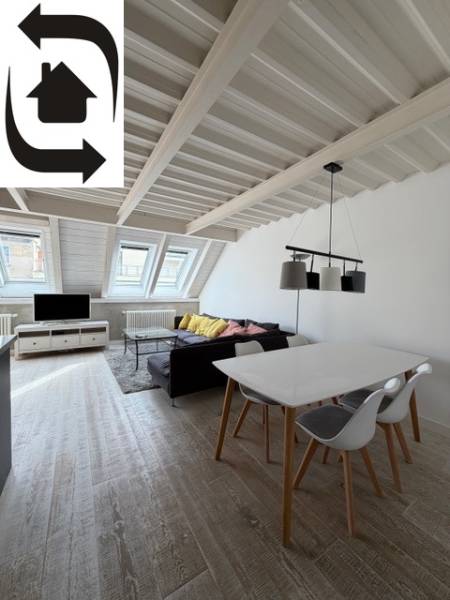 Tetőtéri nappali egy 4 szobás lakásban, fa dekor padlóval és tetőablakokkal.