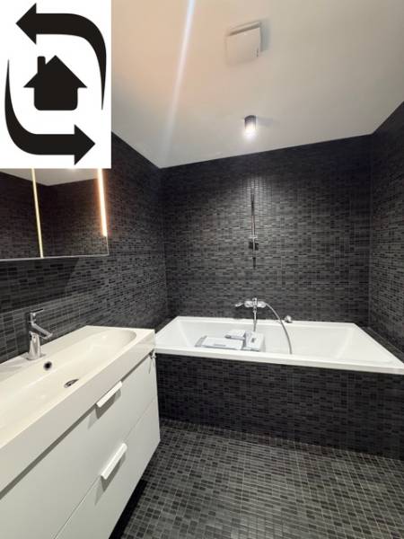 Elegáns fürdőszoba sötét csempékkel és káddal egy 4 szobás lakásban.