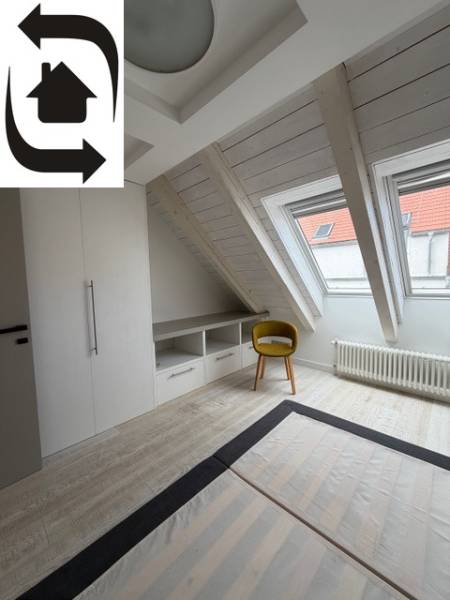 Tetőtéri szoba fa dekorációs padlóval, beépített szekrénnyel és sárga székkel.