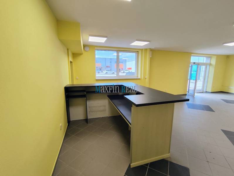 Világos üzlethelyiség pulttal és padlócsempével.