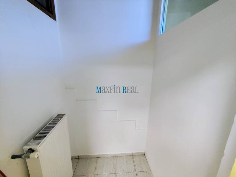 Kereskedelmi helyiségek radiátorral és fehér falakkal, fehér csempével burkolt padló.