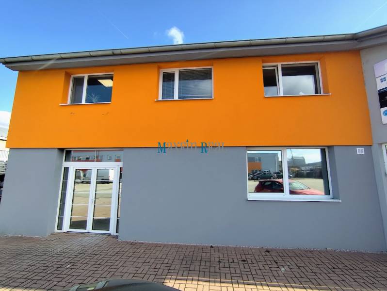 Az épület a Nyitrai Štúrova utcán, világos homlokzatú üzlethelyiségek.