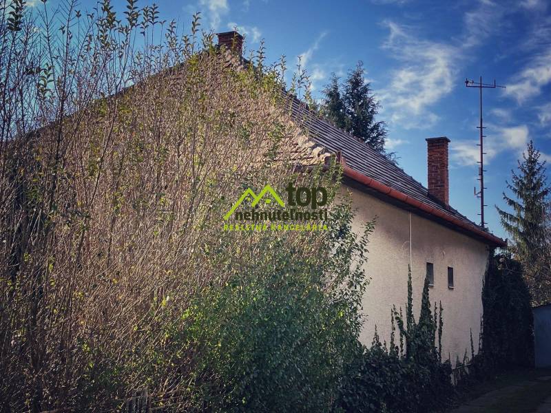 Családi ház Felsőkelebányán, sűrű növényzettel és sűrű fákkal körülvéve.