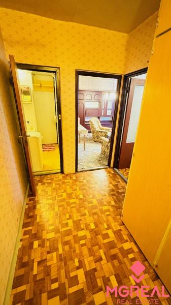 Folyosó egy kétszobás lakásban fa mintázatú padlóval és szobákba nyíló ajtókkal.