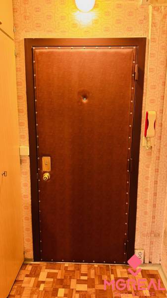 2 szobás lakás bejárati ajtaja fa mintázatú padlóval.