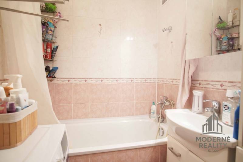 Fürdőszoba káddal, mosdóval és tárolóhellyel egy háromszobás lakásban.