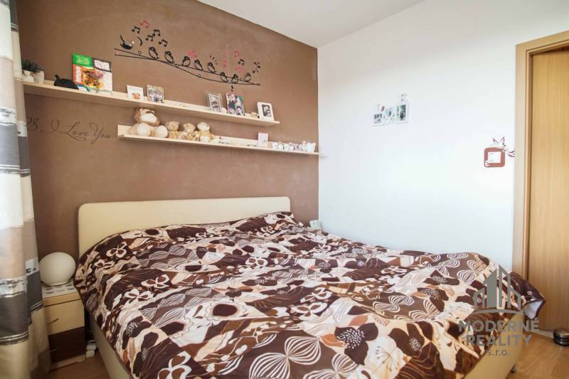 Hálószoba egy háromszobás lakásban, díszített fallal és feltűnő ágyneművel.