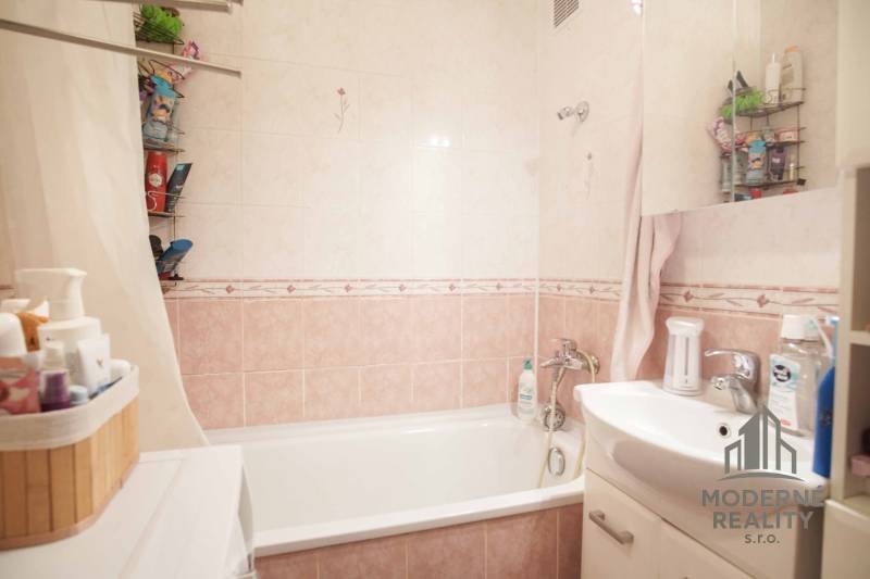 Fürdőszoba káddal és mosdóval egy háromszobás lakásban, csempék finom árnyalatokban.