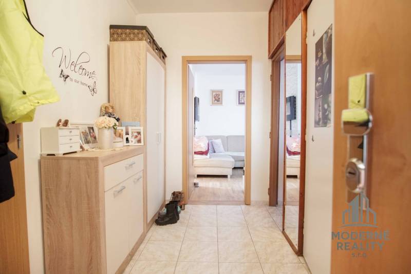 Folyosó egy 3 szobás lakásban csempével és hangulatos, fa dekorációjú bútorokkal.