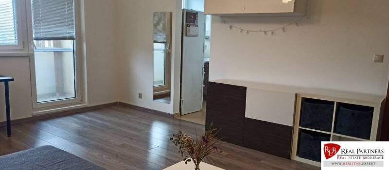 Nappali egy kétszobás lakásban fa dekor padlóval és bútorokkal.