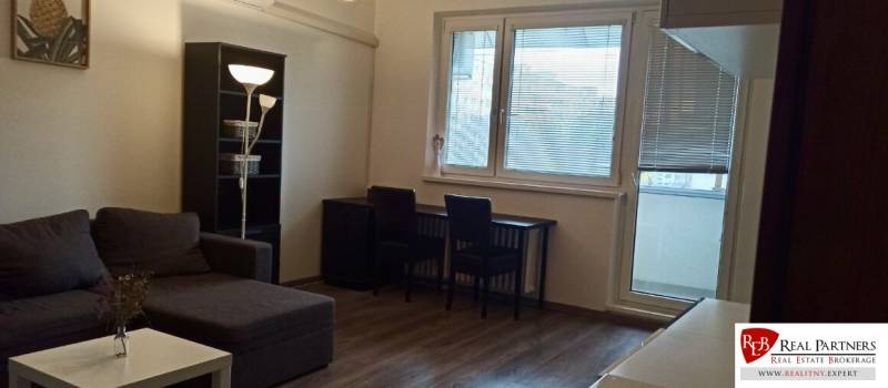 Nappali egy kétszobás lakásban sarokkanapéval és fa dekorációjú padlóval.