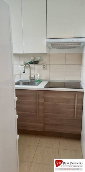 Konyha fehér szekrényekkel és rozsdamentes acél mosogatóval egy kétszobás lakásban.