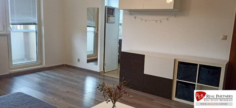 Nappali egy kétszobás lakásban, fa dekor padlóval és erkéllyel.