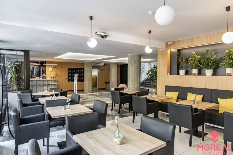 Irodák fa dekor padlóval, asztalokkal, fekete székekkel és növényekkel Pozsonyban.