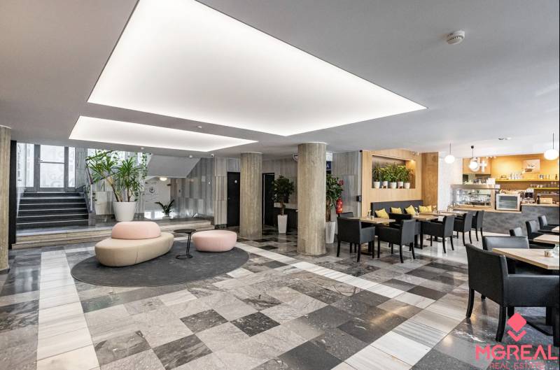 Irodák fekete-fehér padlóval, oszlopokkal, ülőhelyekkel és kávézóval a belső térben.