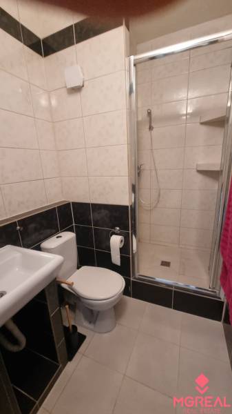 Fürdőszoba mosdóval, WC-vel és zuhanyzóval egy egyszobás lakásban.