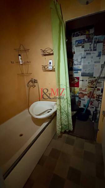 Fürdőszoba káddal és zöld függönnyel a garzonlakásban.